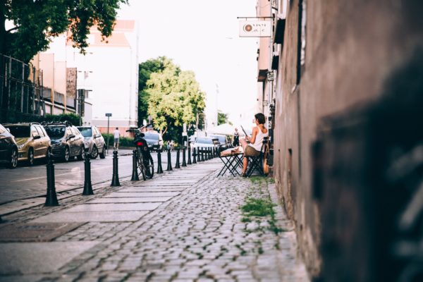 bicycle Buildings Cafe cars casual Chair cobblestone Newspaper Outside Reading Sitting street table travel Urban woman free photo CC0