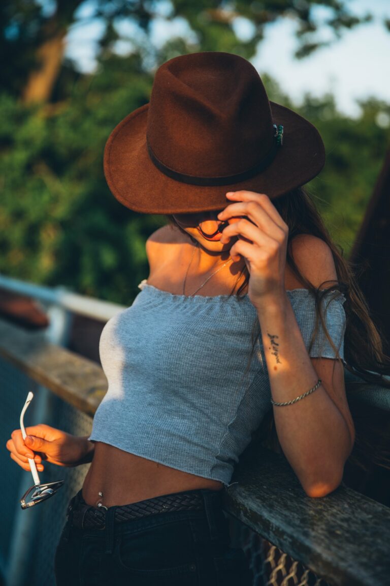 Accessories belly casual Fashion female Fence girl Hat leaning Model nonchalant outdoors Person Relaxing smiling Style Stylish summer sunglasses Sunlight tattoo trees Warm woman free photo CC0